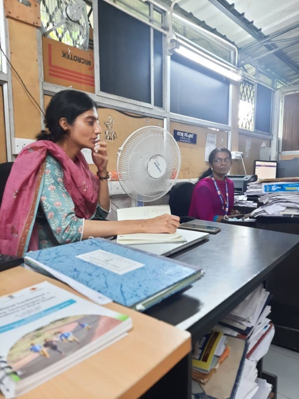A woman at a government office desk, working at a computer.
