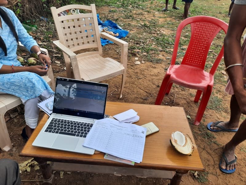 A field workstation: a laptop, papers and a mouse on a table outdoors.